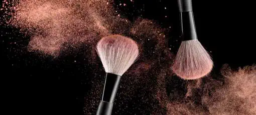 Make-up Artist | Make-up-Bürste mit rosafarbener Pulverexplosion auf schwarzem Hintergrund